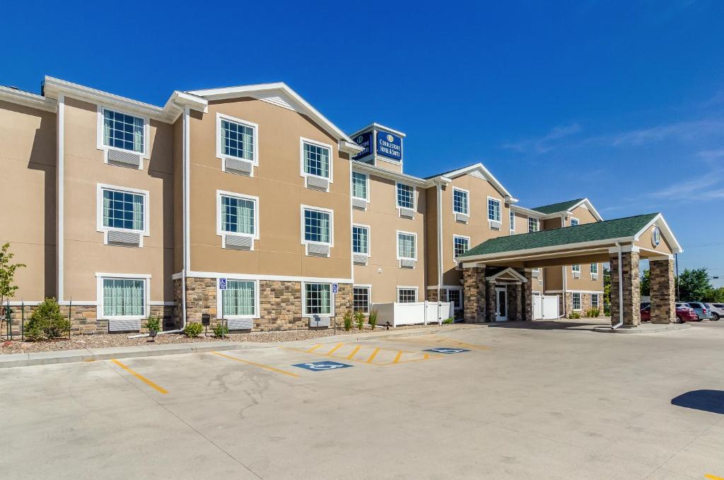 Cobblestone Hotel & Suites - Gering/Scottsbluff في Gering: عمارة سكنية كبيرة مع موقف للسيارة