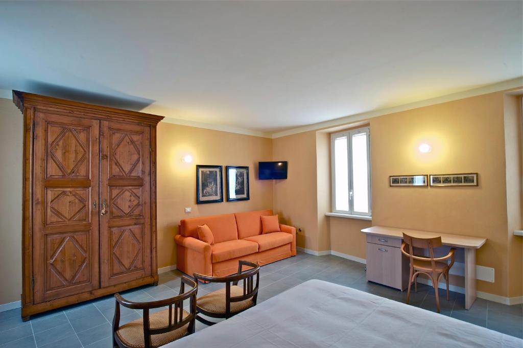 sypialnia z pomarańczową kanapą, stołem i krzesłami w obiekcie Locanda della Maria w mieście Bellagio