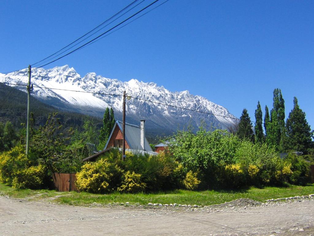 una casa frente a una montaña cubierta de nieve en Alojamiento Las Retamas, en El Bolsón