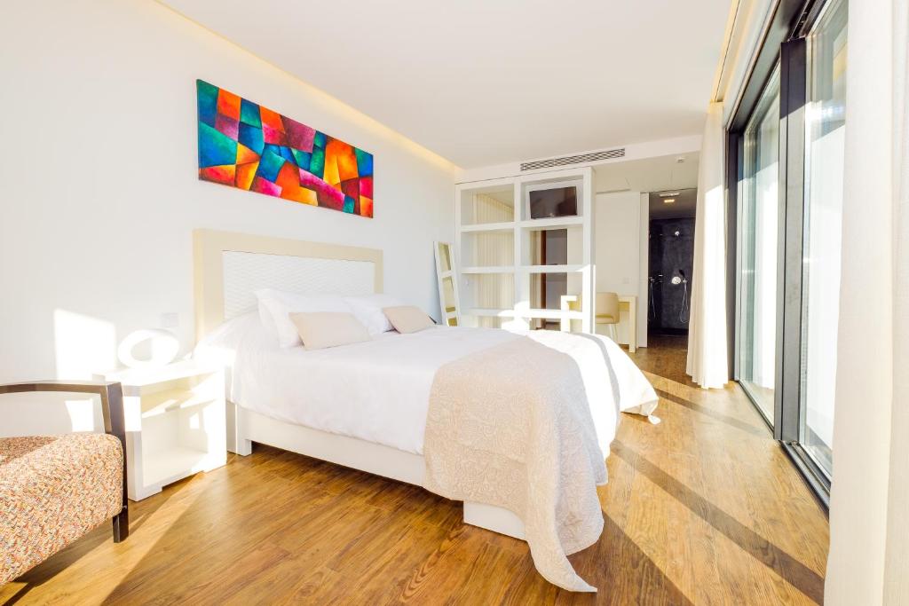 a bedroom with a white bed and a colorful painting on the wall at SISU Guest House in Esposende