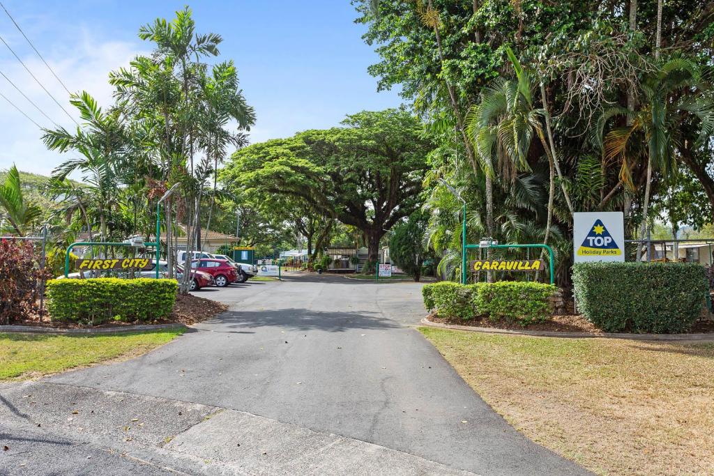 une rue avec des arbres et un panneau indiquant des appartements abordables dans l'établissement First City Caravilla, à Cairns