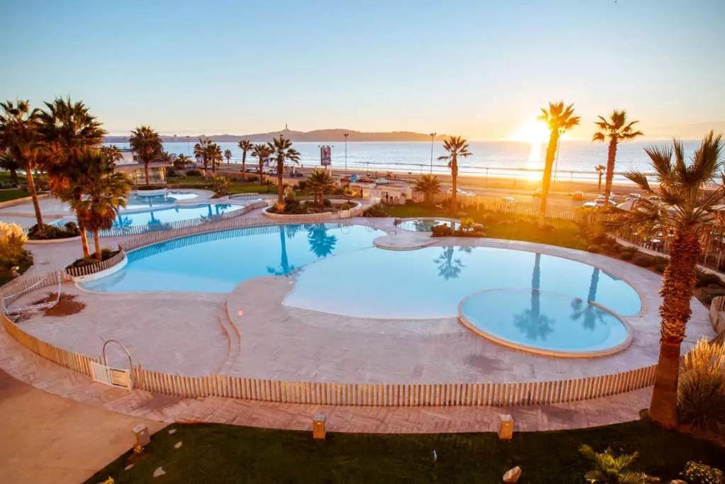 an overhead view of a pool with palm trees and the ocean at Departamento Jardin del Mar La Serena in Coquimbo