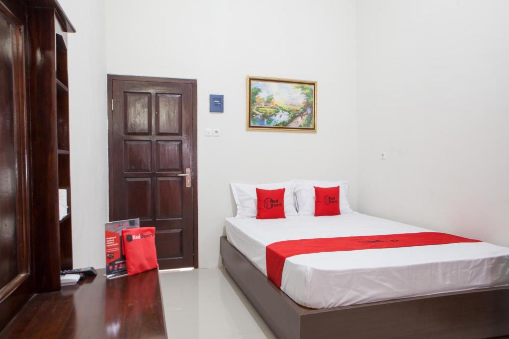 a bedroom with a bed with red pillows and a door at RedDoorz near Banyuwangi Baru Station in Ketapang