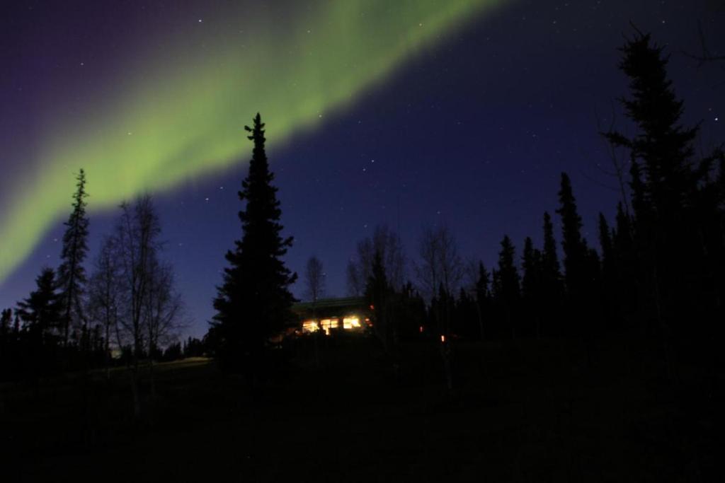 uma imagem de uma casa com a aurora no céu em Northern Sky Lodge em Fairbanks