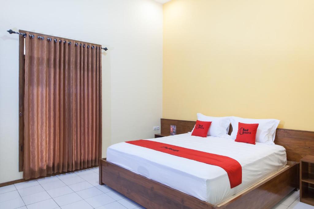 a bedroom with a large bed with red pillows at RedDoorz near Baluran National Park in Pandean