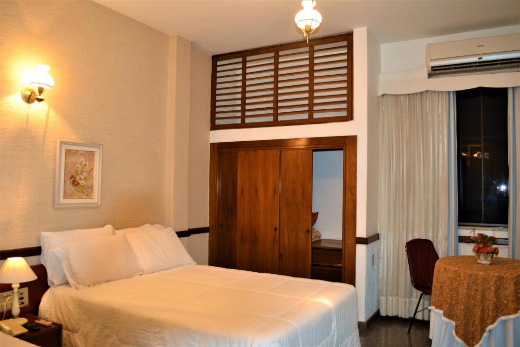 a hotel room with a bed and a window at Hotel Comendador in Três Rios