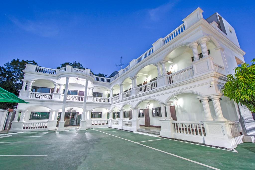 un grand bâtiment blanc avec un parking dans l'établissement Happiness Guesthouse, à Pak Chong