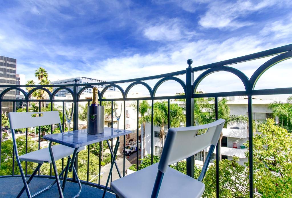 洛杉磯的住宿－Beverly Hills Adjacent 2-Bedroom Penthouse，阳台配有蓝色的桌子和白色的椅子。