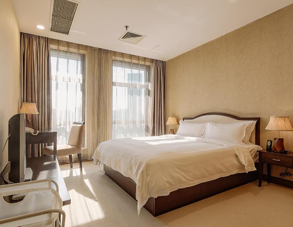 Un dormitorio con una cama grande y una ventana en Dalian Asia Pacific Service Apartment (Former Somerset Harbour Court Dalian), en Dalian