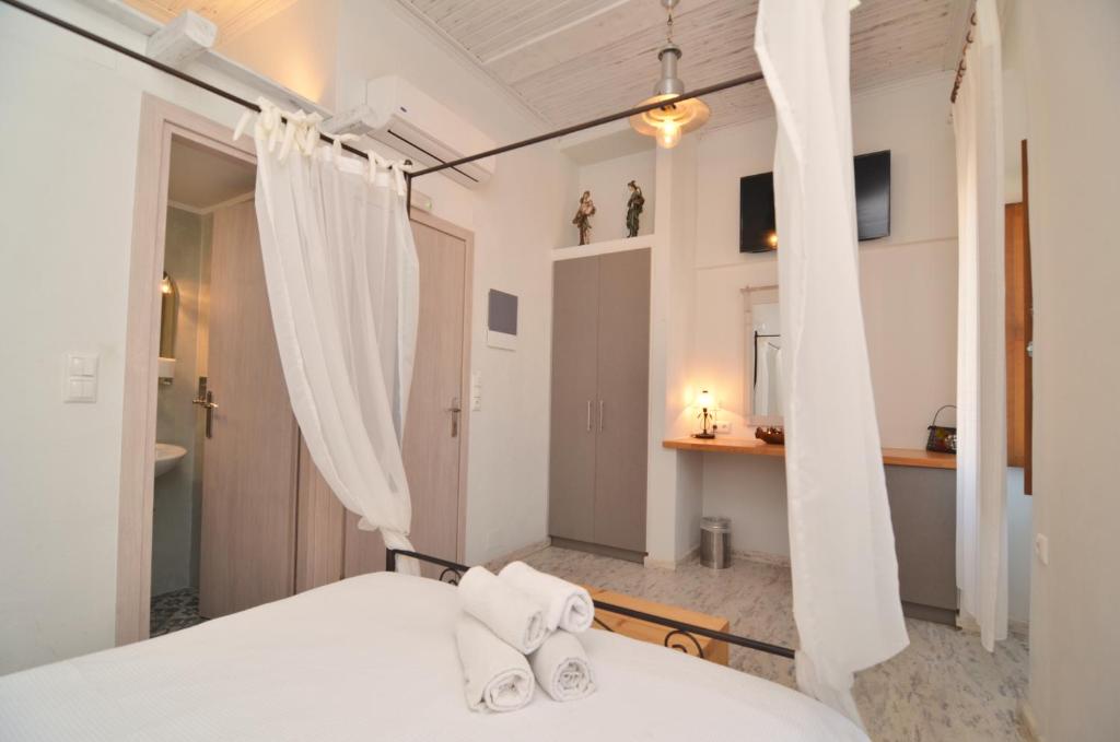 - une chambre avec un lit doté de draps et de rideaux blancs dans l'établissement Sophia Areopoli Guesthouse, à Areópoli