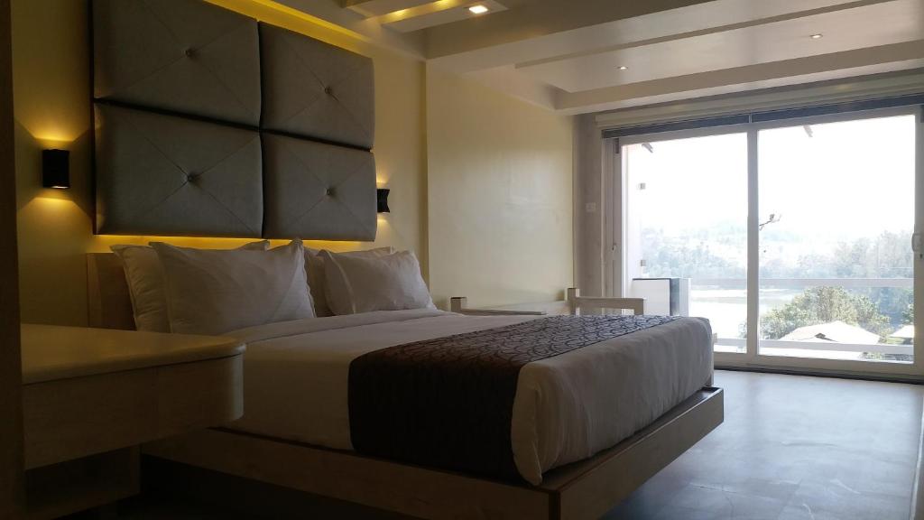 a bedroom with a large bed and a large window at Darshan Resorts Pvt ltd in Ooty