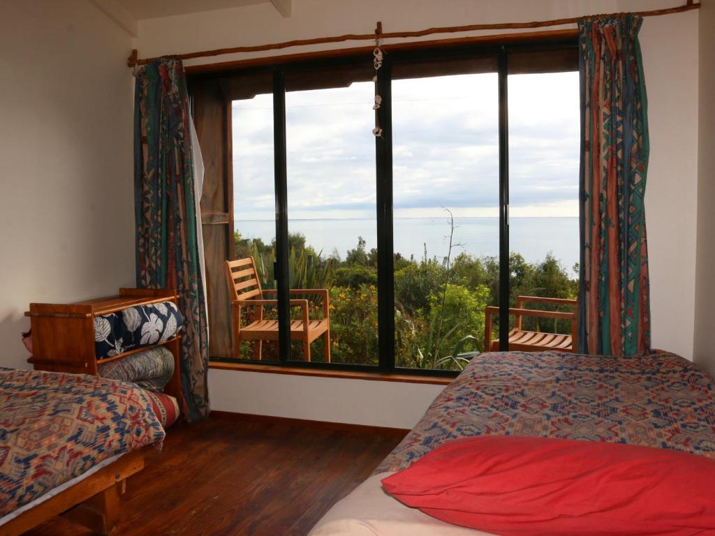 a room with two beds and a large window at Shambhala Cabins in Onekaka
