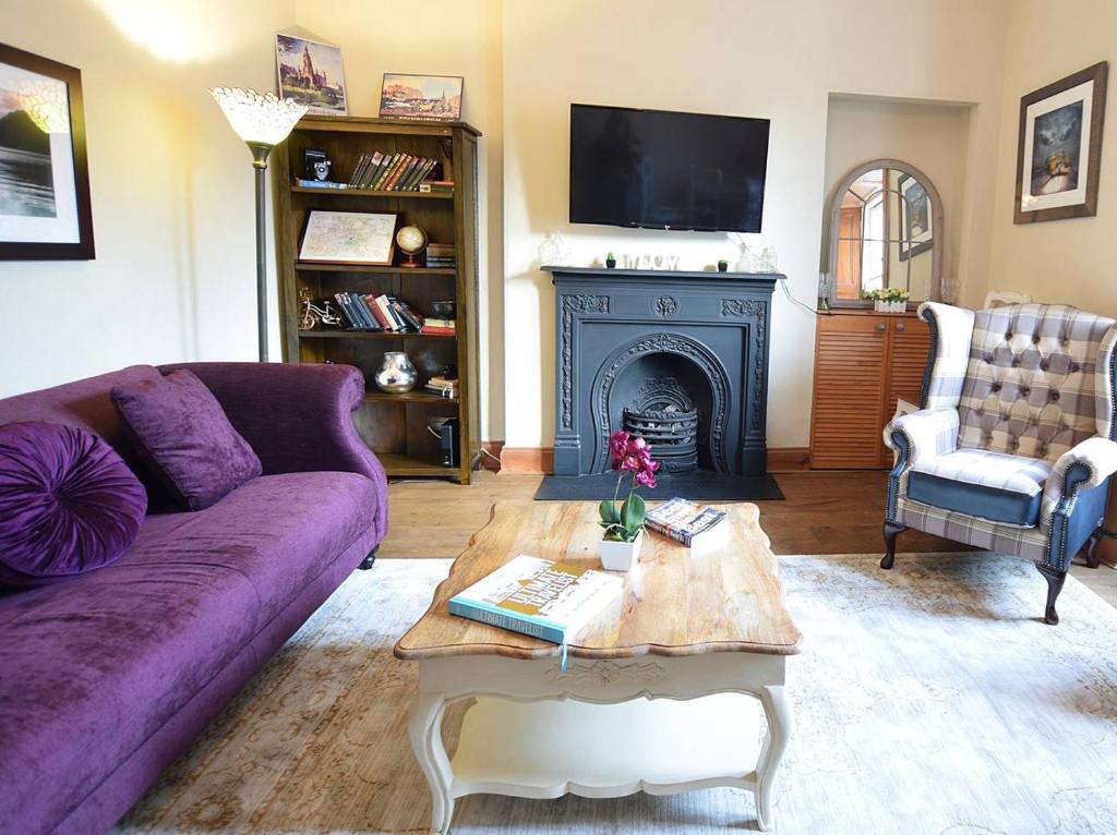 salon z fioletową kanapą i kominkiem w obiekcie ALTIDO Classic 2BR Apartment with Castle Views in Old Town w Edynburgu
