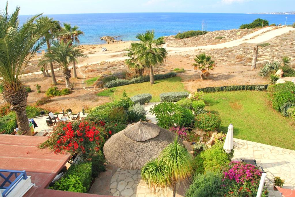 a garden with an umbrella and palm trees and the beach at Sea front Villa Vera in Chlorakas