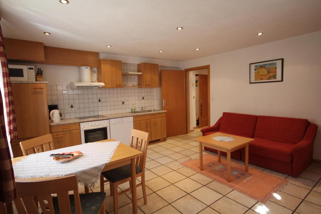 eine Küche und ein Wohnzimmer mit einem roten Sofa und einem Tisch in der Unterkunft Appartementhaus Mentil in Flattach