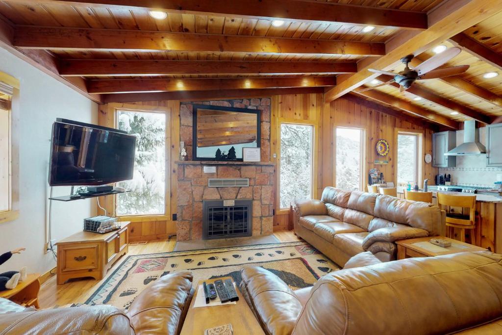 a living room with leather couches and a fireplace at Chipmunk Cabin in Green Mountain Falls
