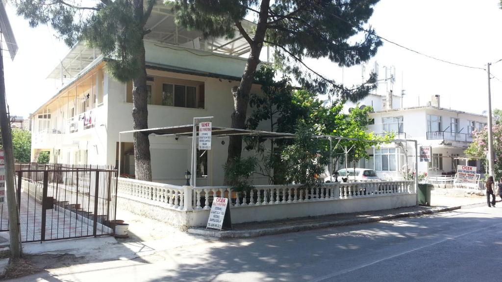 Biały dom z białym płotem obok ulicy w obiekcie Cicek Aile Pansiyonu w mieście Burhaniye