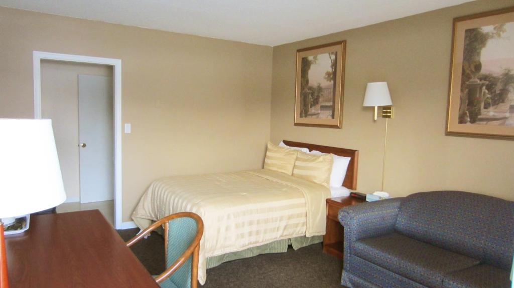 een hotelkamer met een bed en een stoel bij Village Inn & Suites - Sudbury in Lively