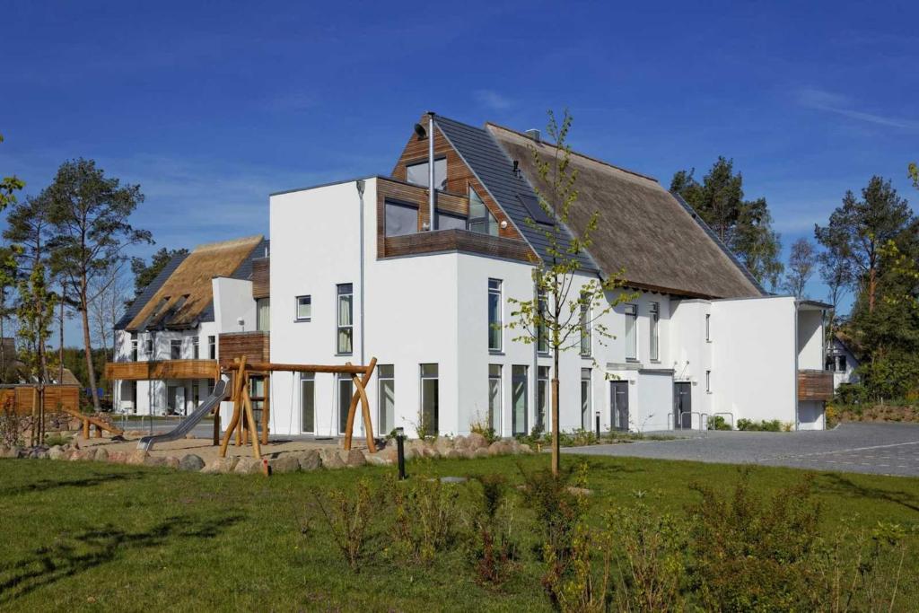 een wit huis met een bruin dak bij Lotsenstieg 2 Kajuete 03 in Ostseebad Karlshagen