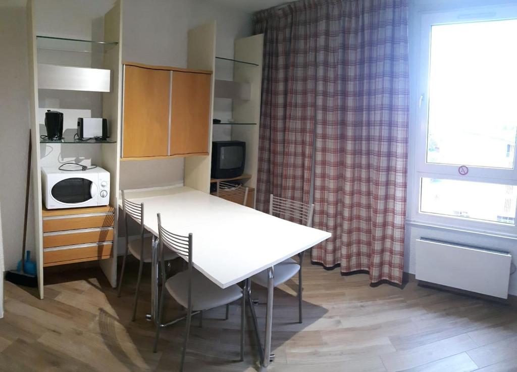 a kitchen with a white table and a microwave at Le Champame in Mont-de-Lans