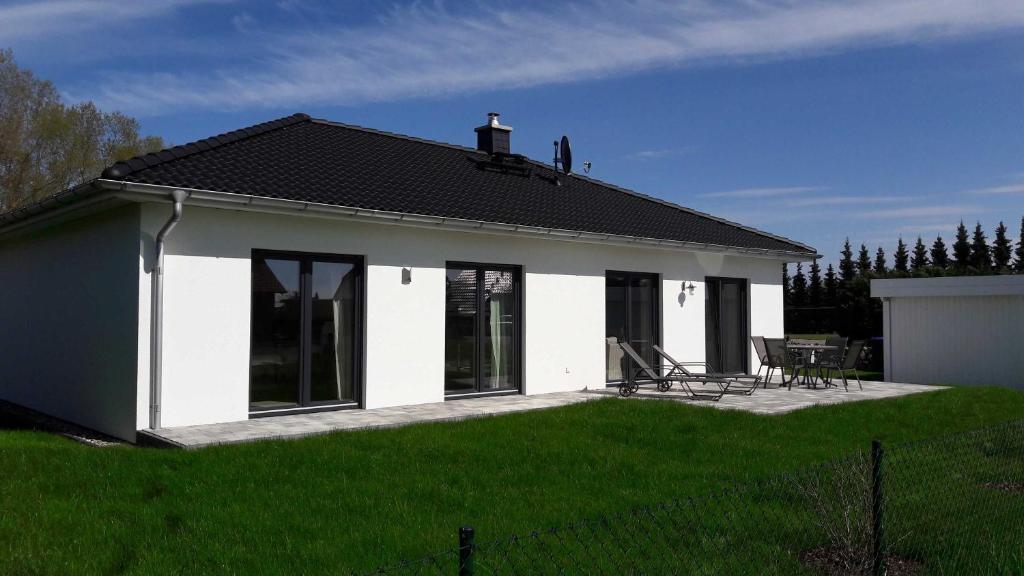 een klein wit huis met een patio en groen gras bij Karlshagen Haus Frieda in Ostseebad Karlshagen