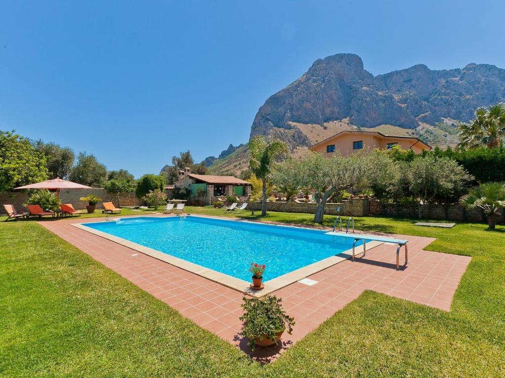 a swimming pool in a yard with mountains in the background at Belvilla by OYO Carta Dieci in Cinisi