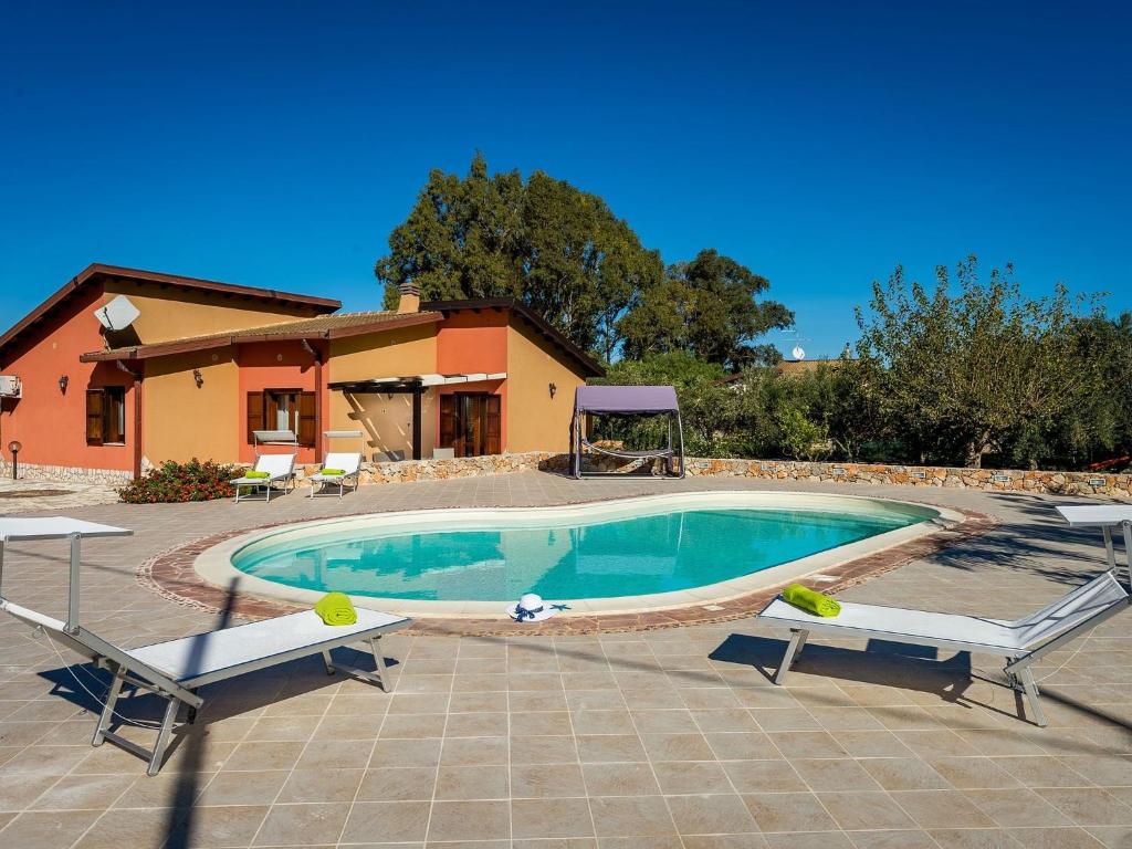 a swimming pool with two benches in front of a house at Belvilla by OYO Beautiful Holiday Home near Beach in Castellammare del Golfo