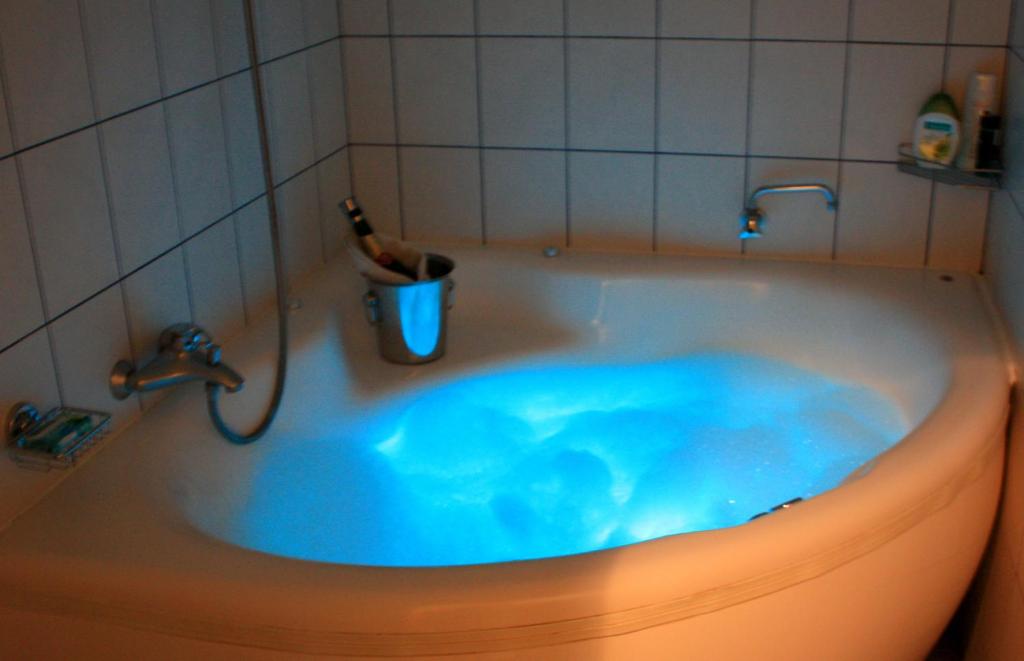 a bath tub with blue water in a bathroom at Guest House &Scaron;ampētera māja in Rīga