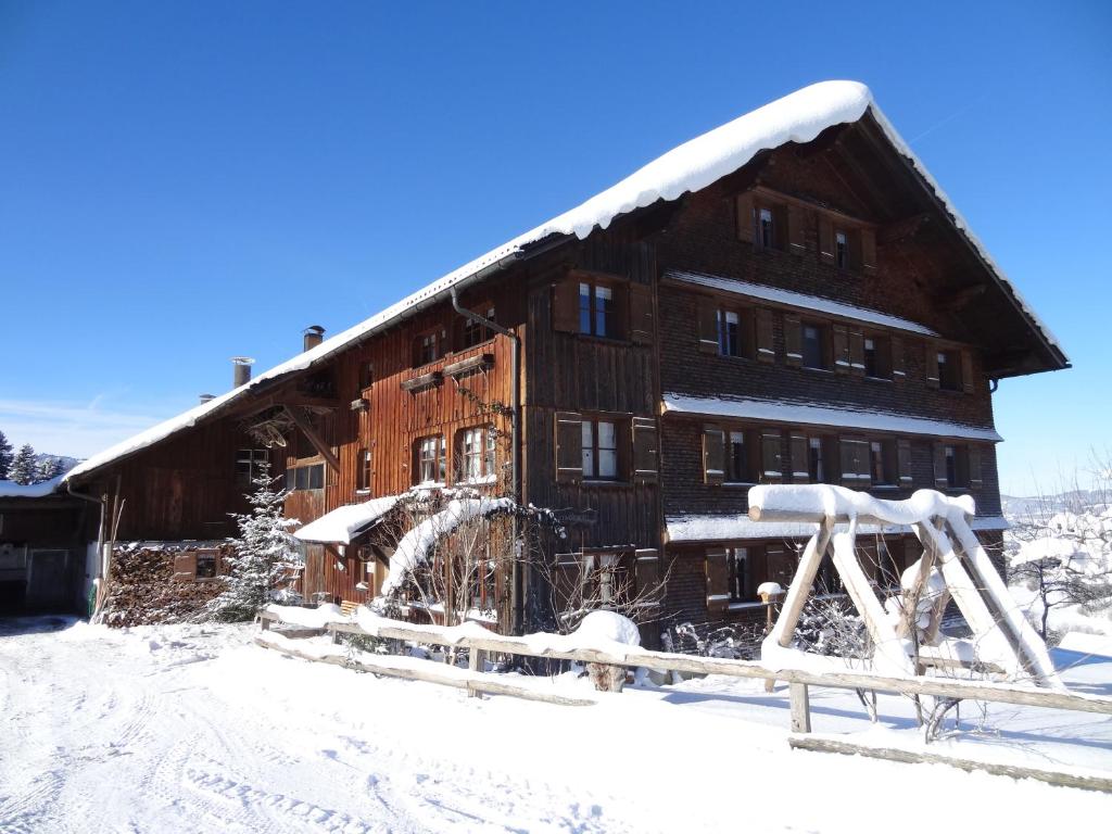 duży drewniany budynek pokryty śniegiem w obiekcie Bauernhof Schneider w mieście Egg