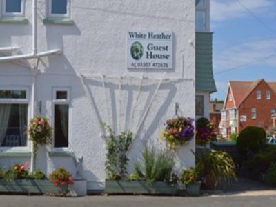 a white building with a sign for a guest house at White Heather Guest House in Mablethorpe