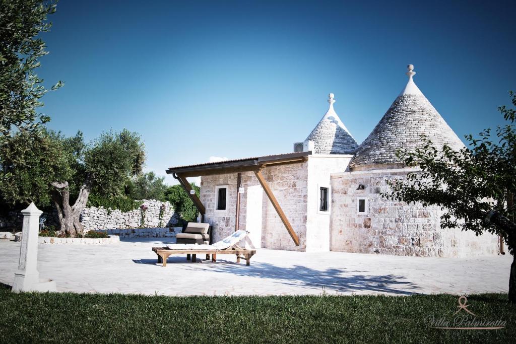 卡斯特拉納格羅泰的住宿－Villa Palmirotta Trulli Relais，石头建筑,前面有长凳