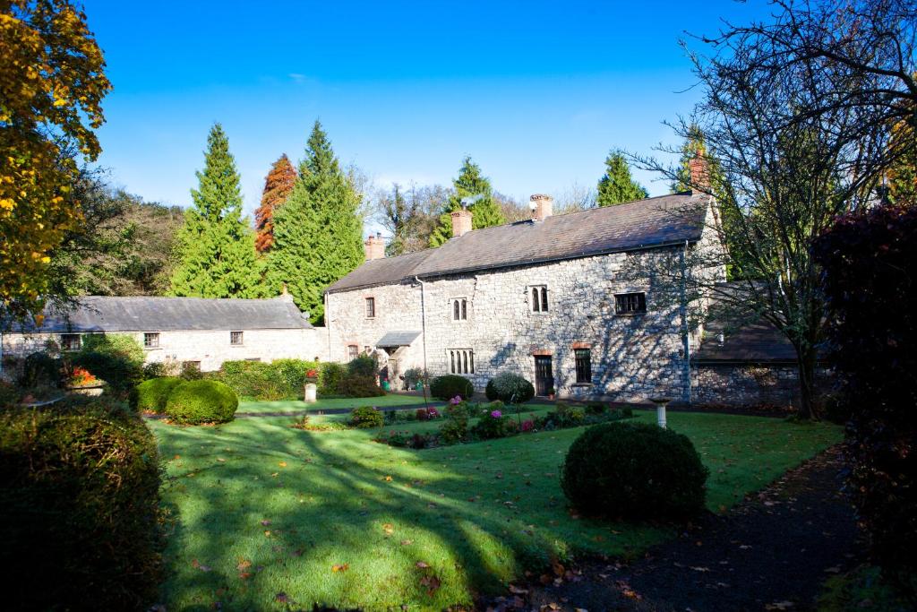 an old stone house with a garden in front of it at Pencoed House Estate (Cardiff) in Cardiff