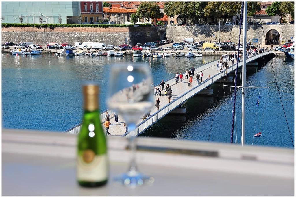 una bottiglia di vino e un bicchiere di vino sul davanzale della finestra di Eden Penthouse Apartments a Zara (Zadar)