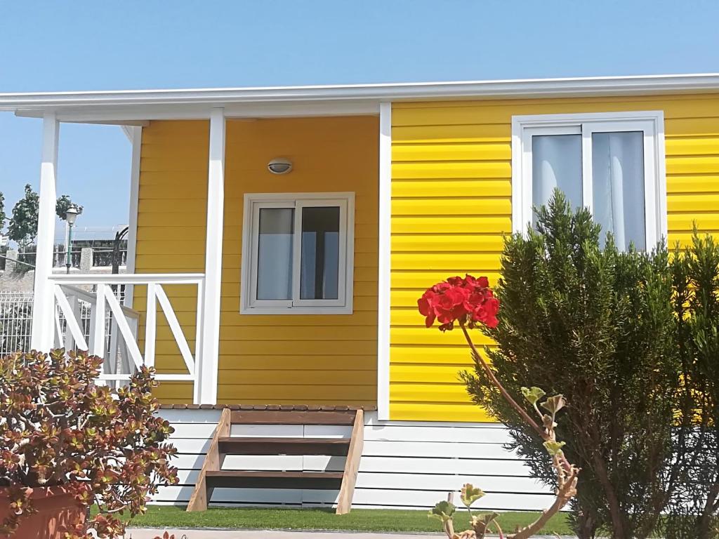 ein gelbes Haus mit einer weißen Veranda und einem Fenster in der Unterkunft CAMPING BAHIA SANTA POLA in Santa Pola