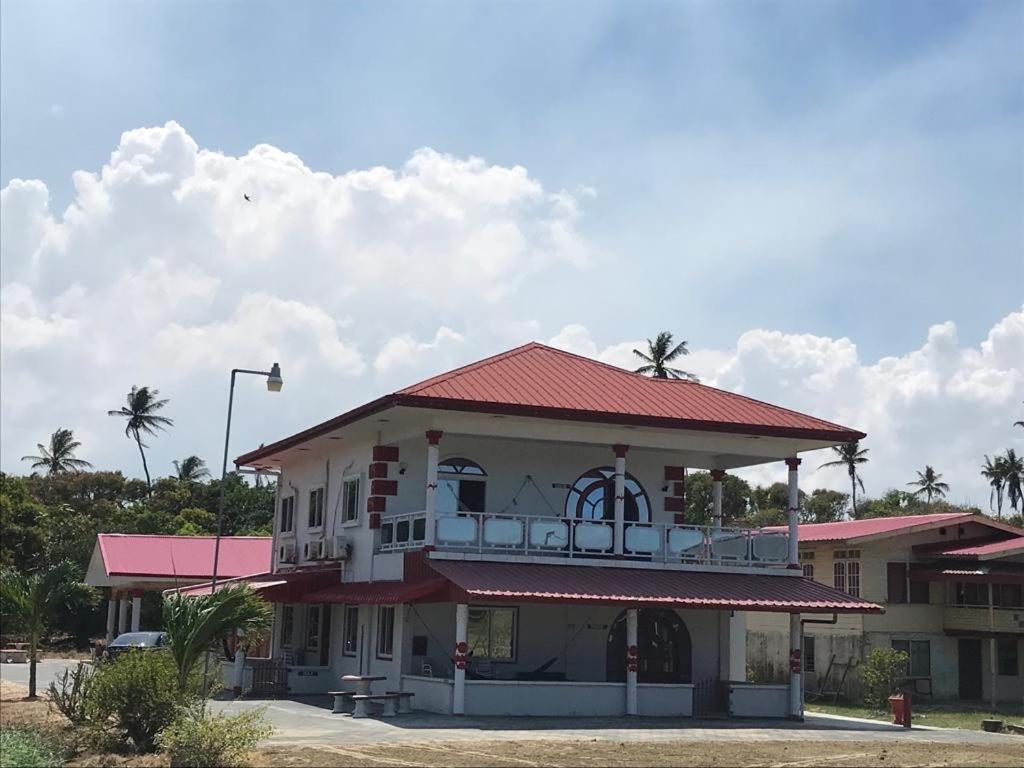 ein Gebäude mit einem roten Dach mit Palmen in der Unterkunft Zeedijk Resort Nickerie in Nieuw Nickerie
