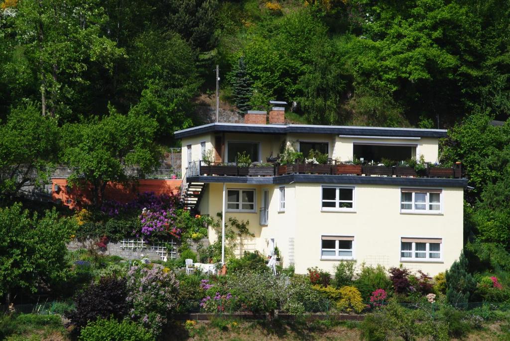 Cette maison blanche dispose d'un balcon fleuri. dans l'établissement Ferienwohnung Haus am Sommerberg, à Ludwigsstadt
