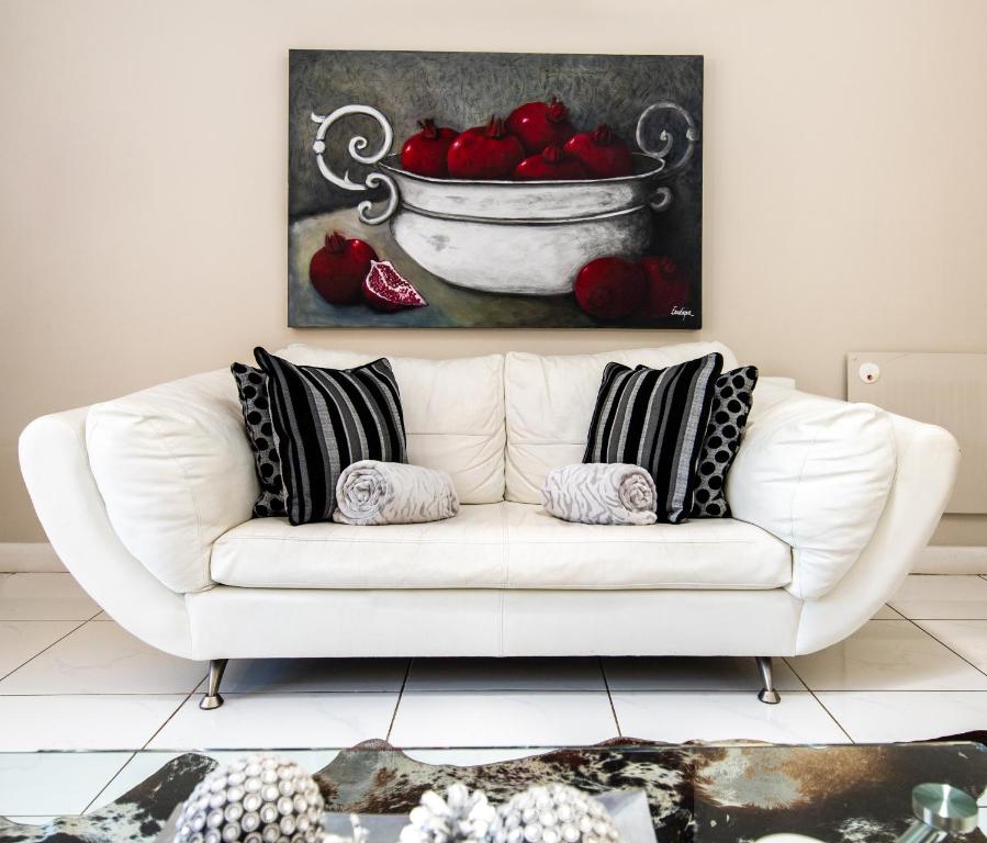 un sofá blanco con almohadas y una pintura de un tazón de tomates en Montagu Four Seasons, en Montagu