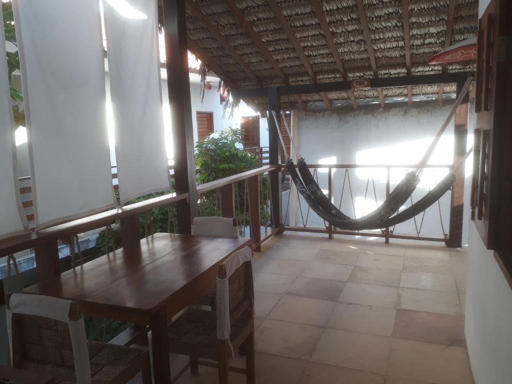 a porch with a wooden table and a hammock at Guaco House in Jericoacoara