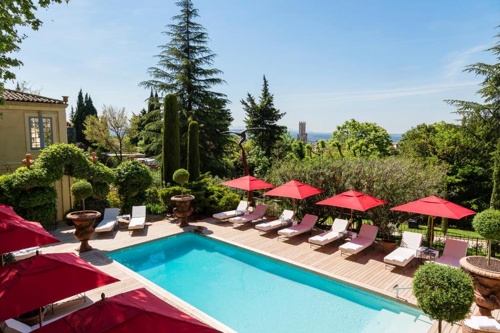 a swimming pool with chairs and red umbrellas at Villa Gallici Hôtel & Spa in Aix-en-Provence