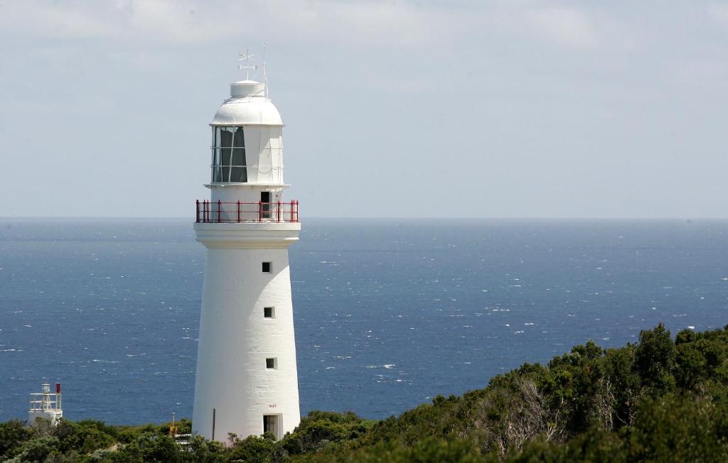 Biała latarnia morska na szczycie wzgórza w pobliżu oceanu w obiekcie Cape Otway Lightstation w mieście Cape Otway