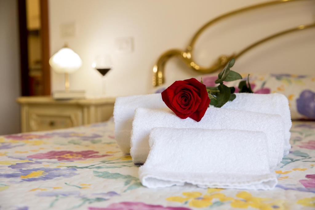 einen Haufen Handtücher mit einer Rose auf dem Bett in der Unterkunft le terme sotto casa in Rapolano Terme