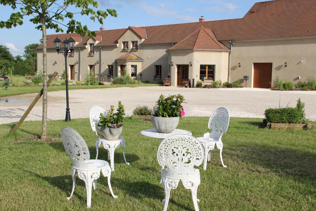a group of white chairs and a table in a yard at Le Manoir des Arômes in Brugny-Vaudancourt