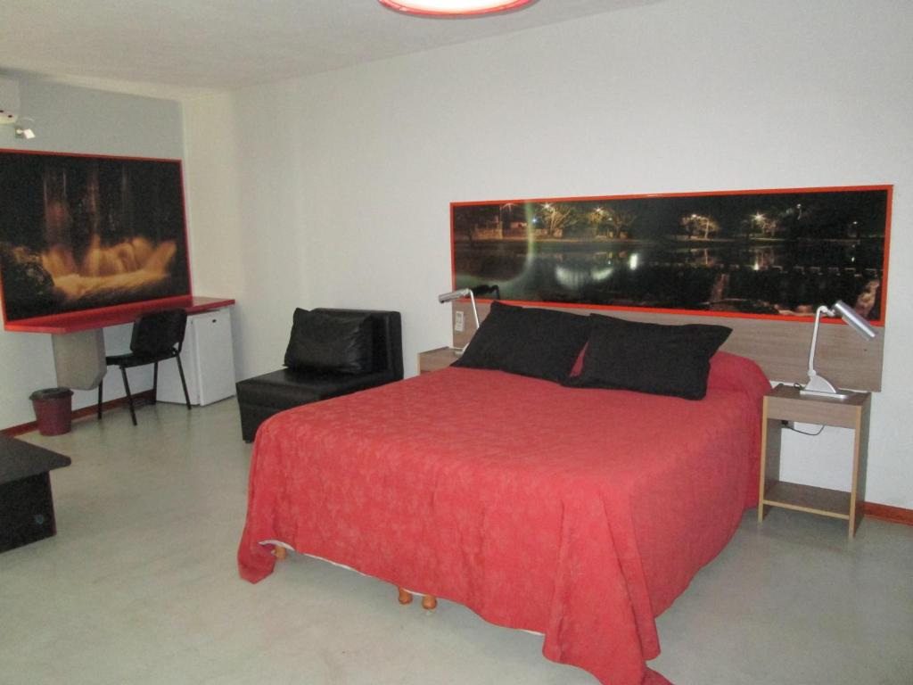 1 dormitorio con 1 cama roja y 1 silla en Cañas Suites Urbanas en Mina Clavero