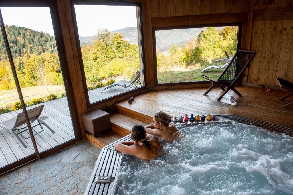 two people sitting in a hot tub in a house at Là Haut & Spa in Ventron