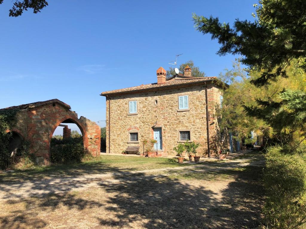 una vieja casa de piedra con un arco delante de ella en Antico Casale Silvia, en Alberoro