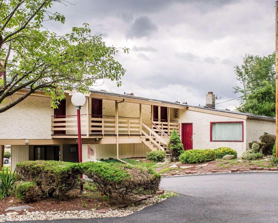 una casa con una puerta roja y un árbol en Econo Lodge Summit - Scranton, en Clarks Summit