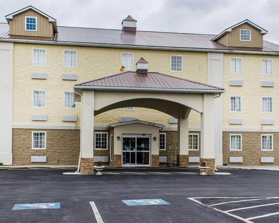 a large building with an archway in a parking lot at SureStay Plus by Best Western Jonestown Lebanon Valley in Jonestown