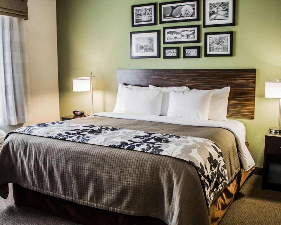 a bed in a hotel room with pictures on the wall at Sleep Inn & Suites Harrisburg -Eisenhower Boulevard in Harrisburg