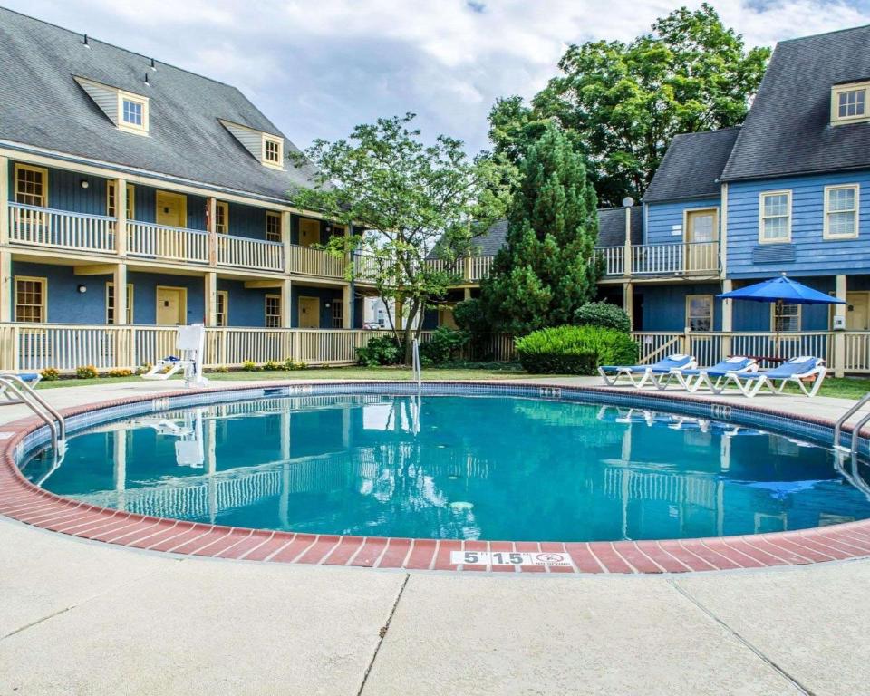 a large swimming pool in front of a building with chairs at Clarion Inn Strasburg - Lancaster in Strasburg