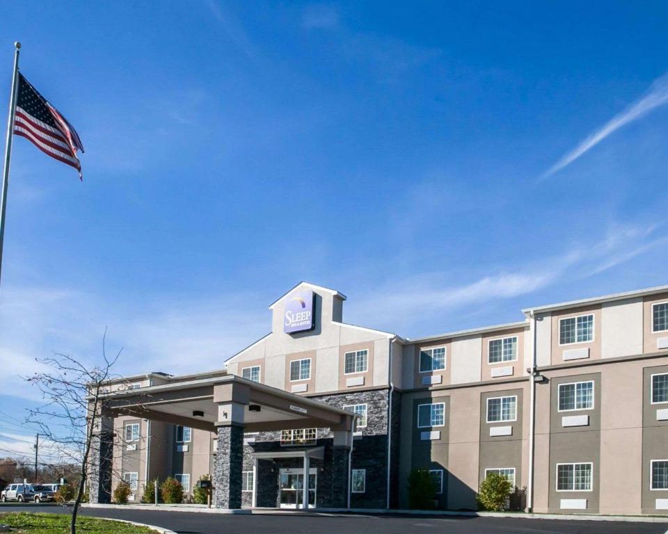 a hotel with an american flag in front of it at Sleep Inn & Suites Harrisburg – Hershey North in Harrisburg